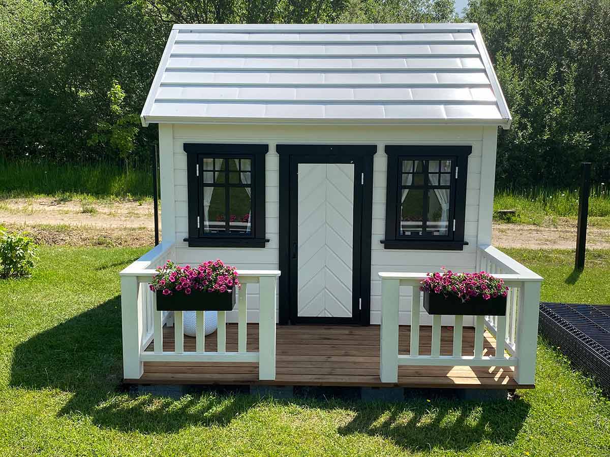 Custom Playhouse from Front with wooden terrace with white railings and black flower boxes by WholeWoodPlayhouses 
