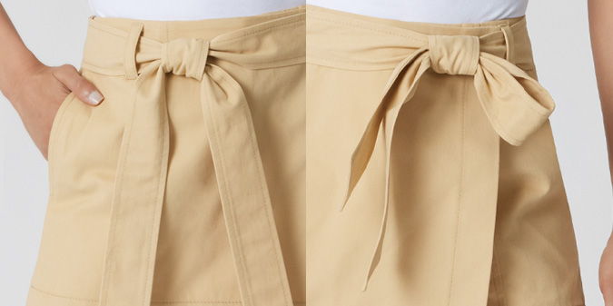 Close-up of a beige skirt with a tied bow detail.