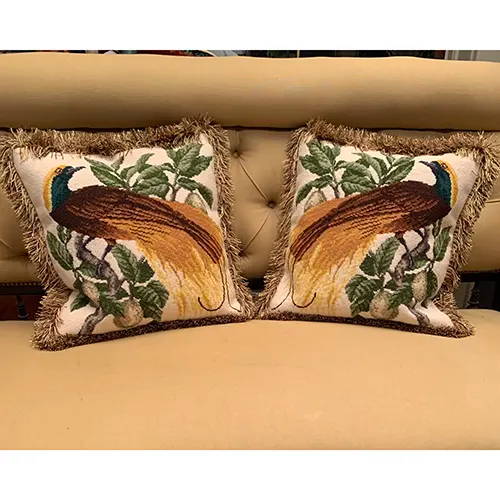 Two finished Emperor needlepoint pillows on couch