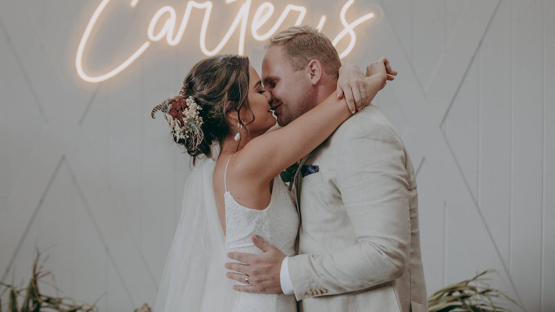 Brides arms wrapped around her new husbands neck 