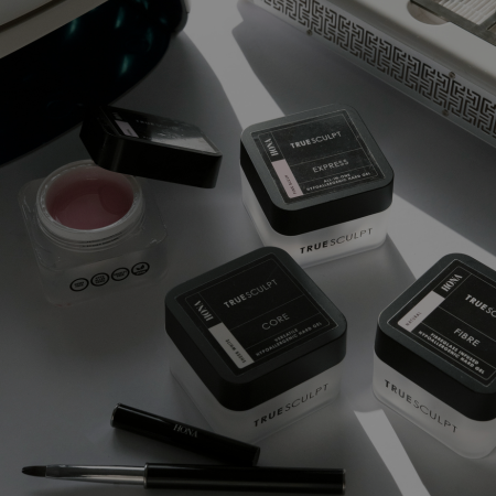 Cosmetic products arranged on a reflective surface with tools.