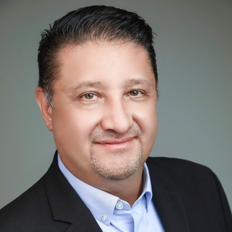 Professional man in a suit smiling against a neutral background.
