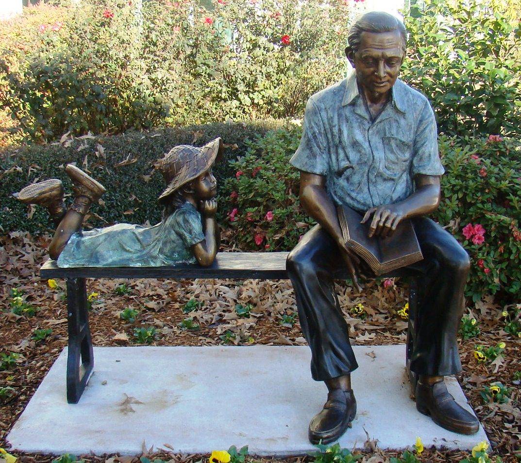 Bronze statue of a grandfather and granddaughter sitting on a bench