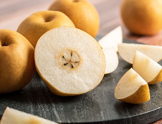 Sliced and whole pears on a dark surface, showcasing their interior and exterior.