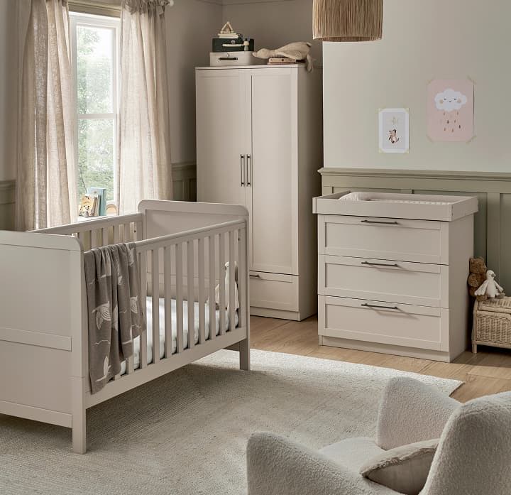 A cozy nursery with a crib, dresser, and wardrobe in soft colors.