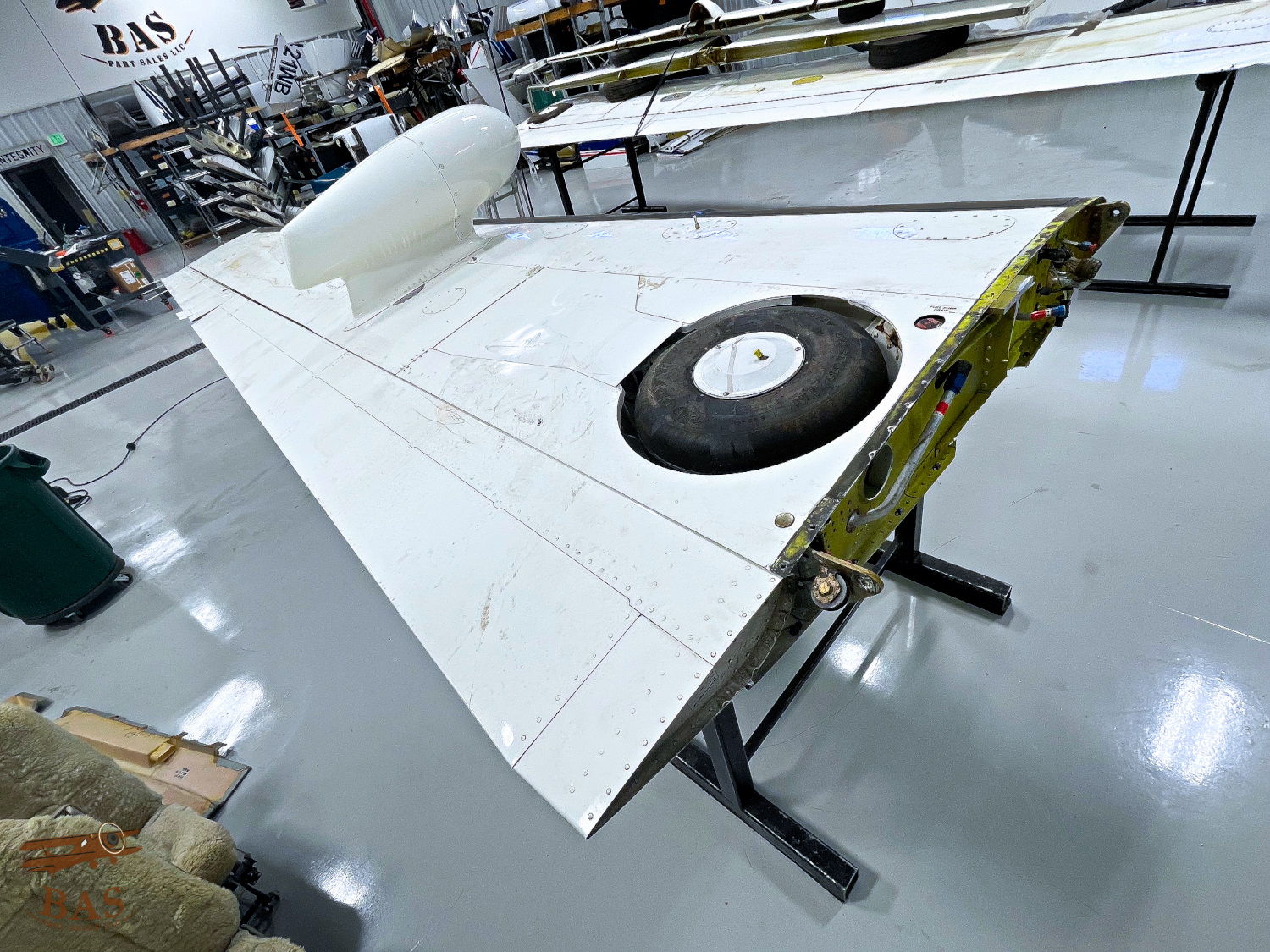 Aircraft wing section displayed in a workshop, showing details and equipment.