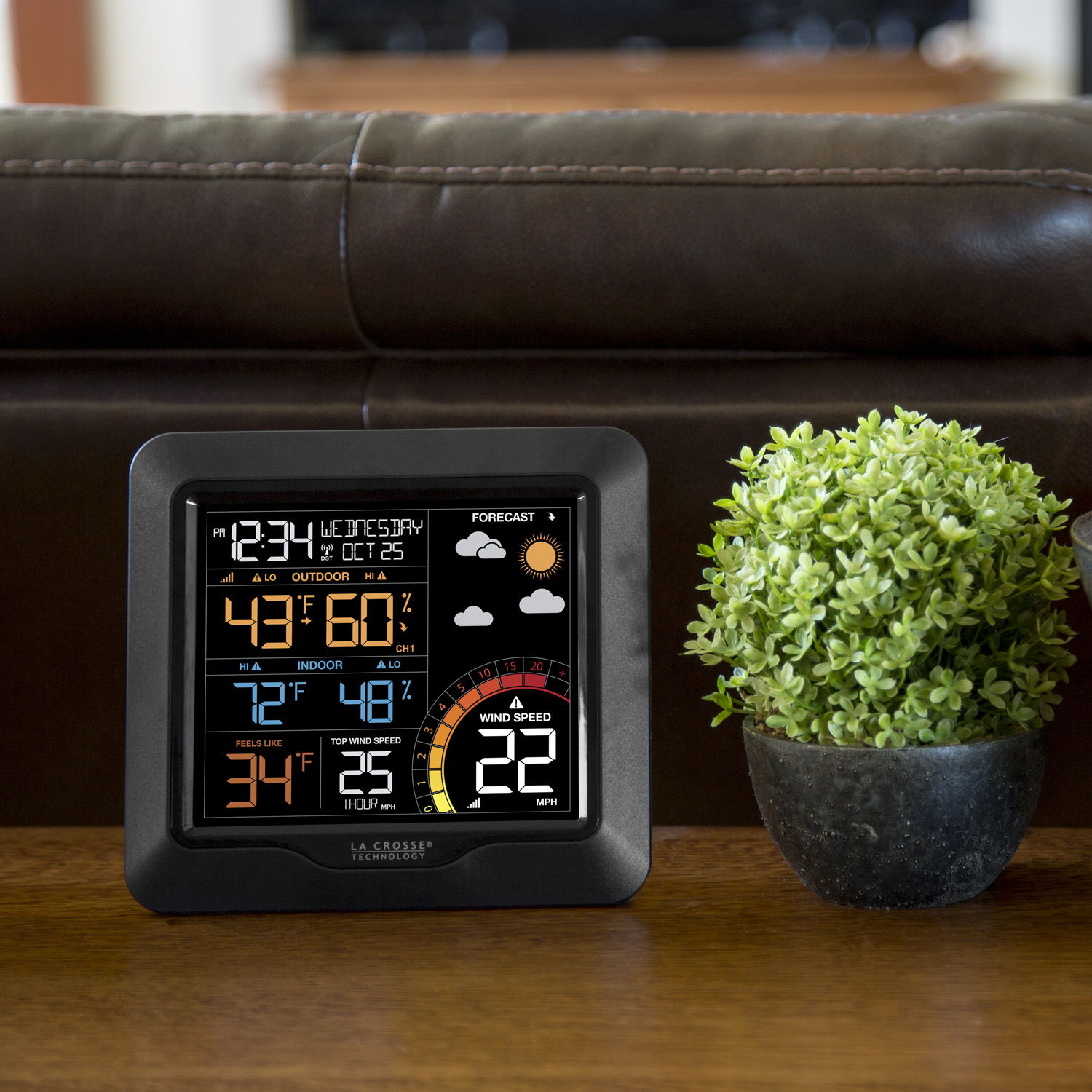 327-1417 Digital weather station with wind sitting next to a small potted plant on a table.