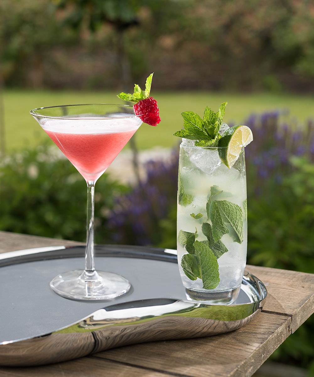 Two colorful cocktails on a Drift Serving Tray in a garden setting.