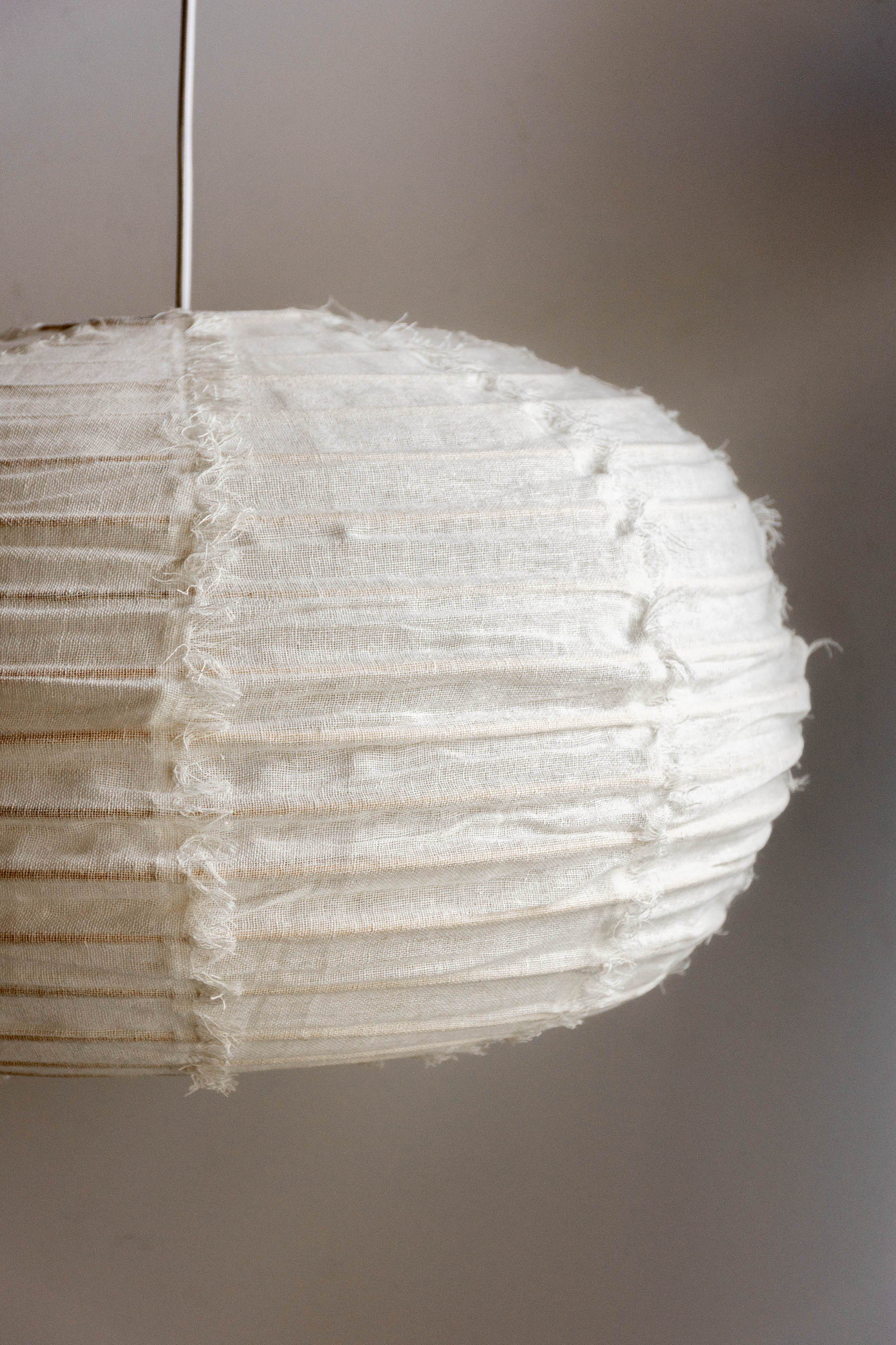 White fabric pendant lamp with a textured, oval shape.