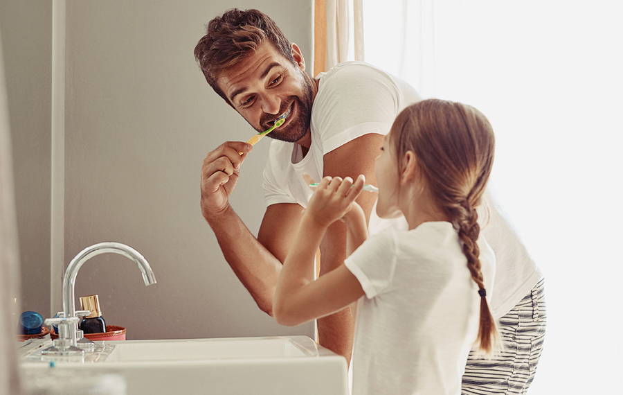 father and daughter brushing their teeth
