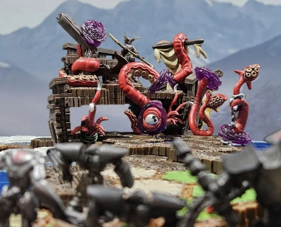 Colorful fantasy miniatures on a scenic tabletop battlefield.