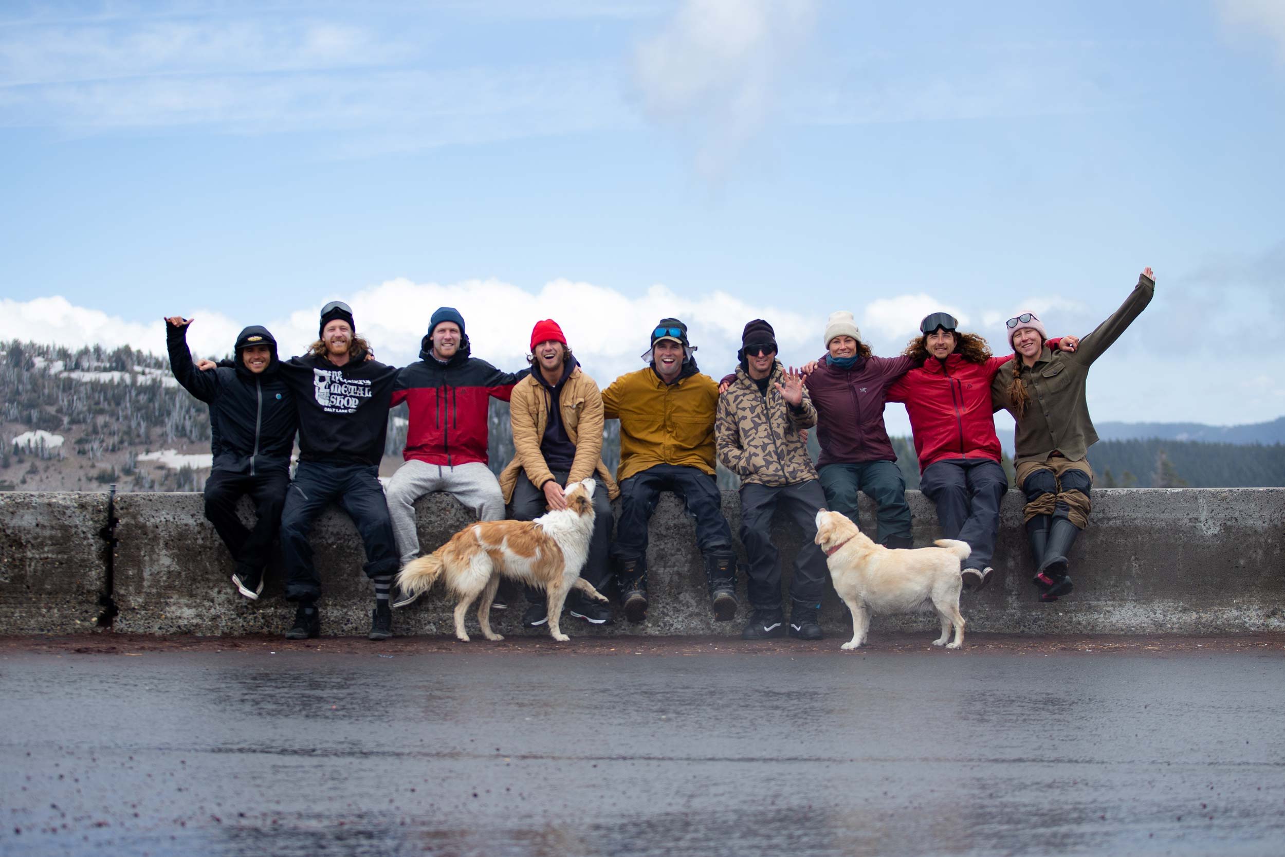 Group of people with dogs outdoors, smiling and posing together.