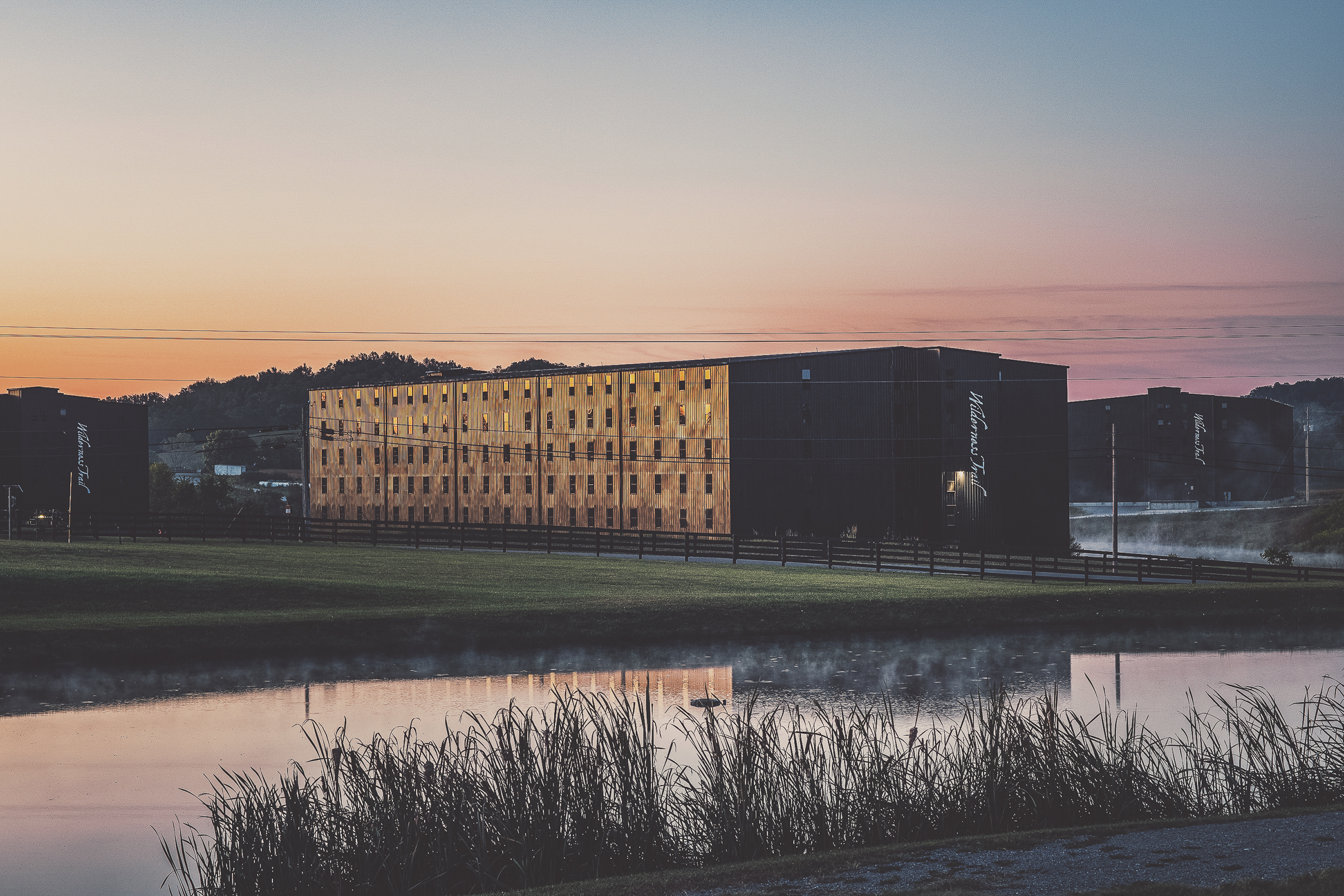 Modern building at sunset reflected in water.