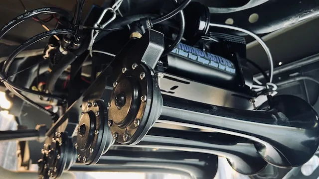 Close-up glossy black train horns HornBlasters logo compressor air lines zip ties mounting brackets Stephen's 2020 Tundra 244 Spare Tire Delete gallery photo 2