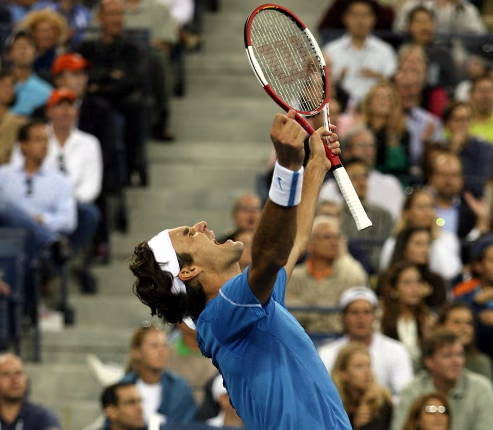 Tennis player celebrating a point next to a tennis racket.