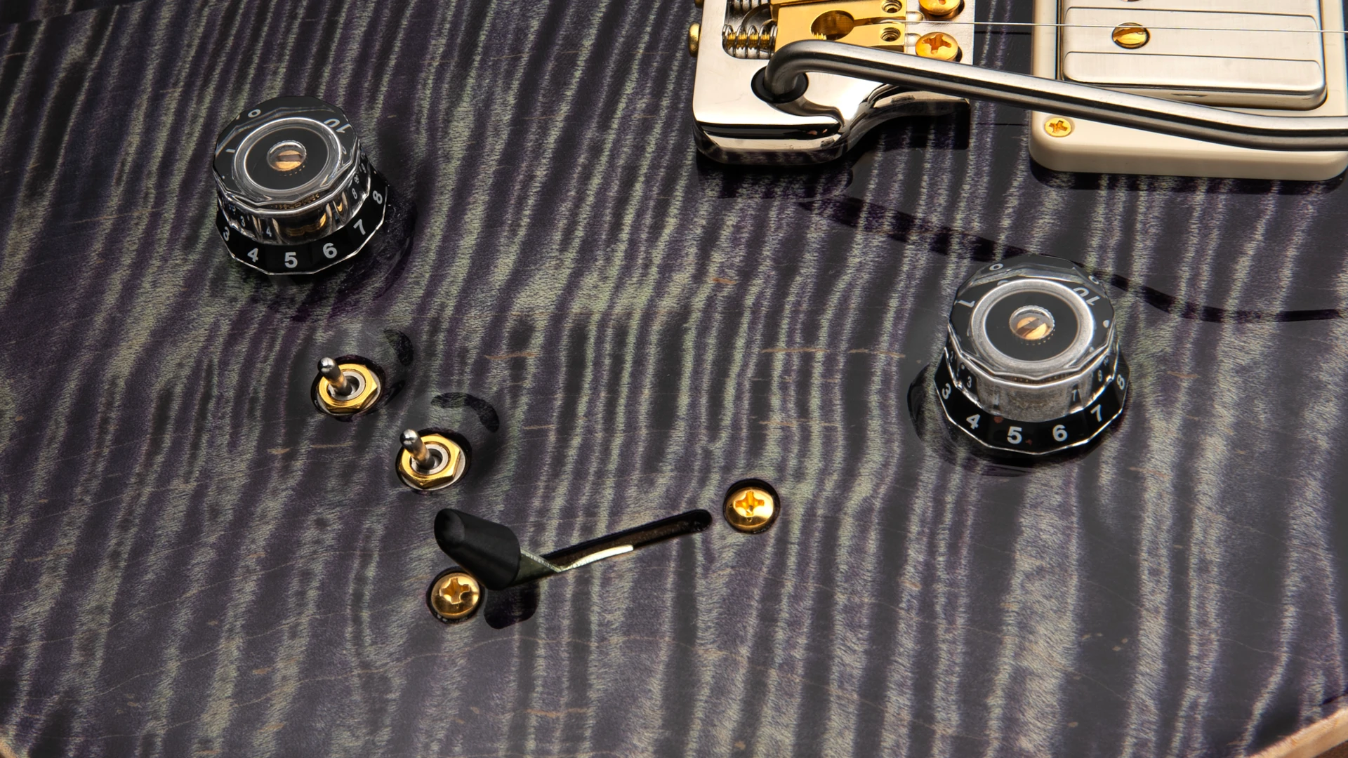 Close-up of a PRS guitar body showing knobs and control switches.