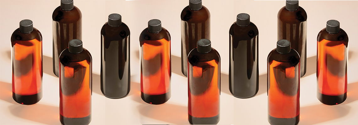 Brown glass bottles arranged in two rows with orange liquid inside.