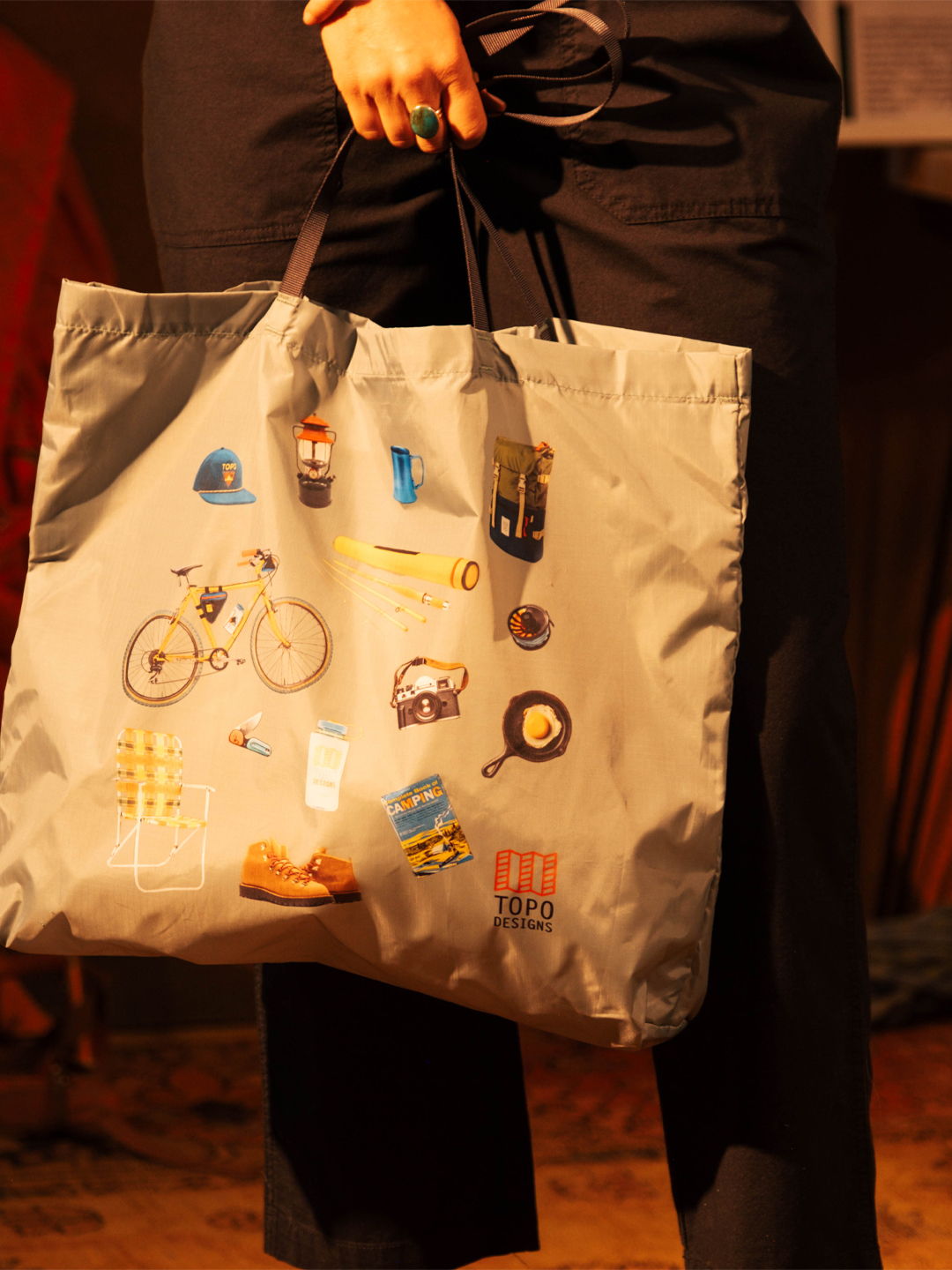 A person holding a tote bag with colorful graphic designs.