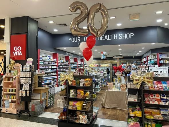A health shop celebrating its 20th anniversary with balloons and products displayed.