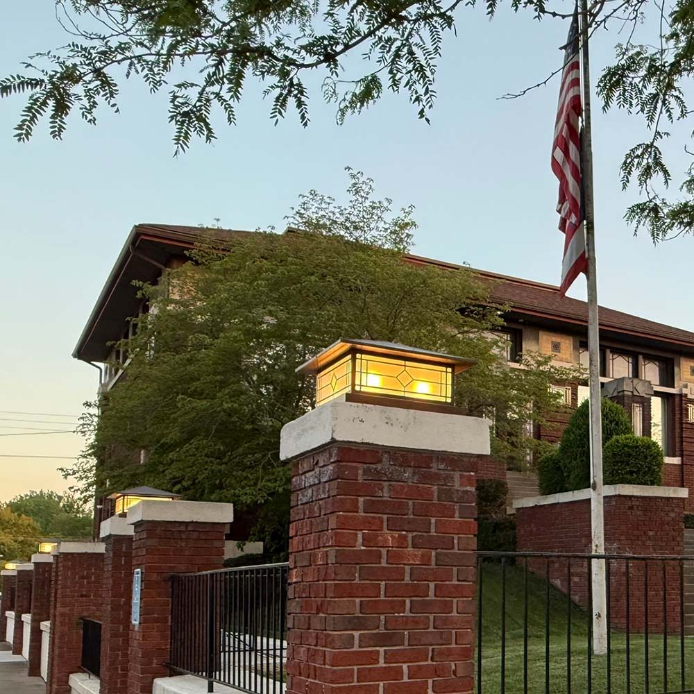 A customer installation photo of shallow pier lights with a raw copper finish. They're on the fence of a library in Ohio.