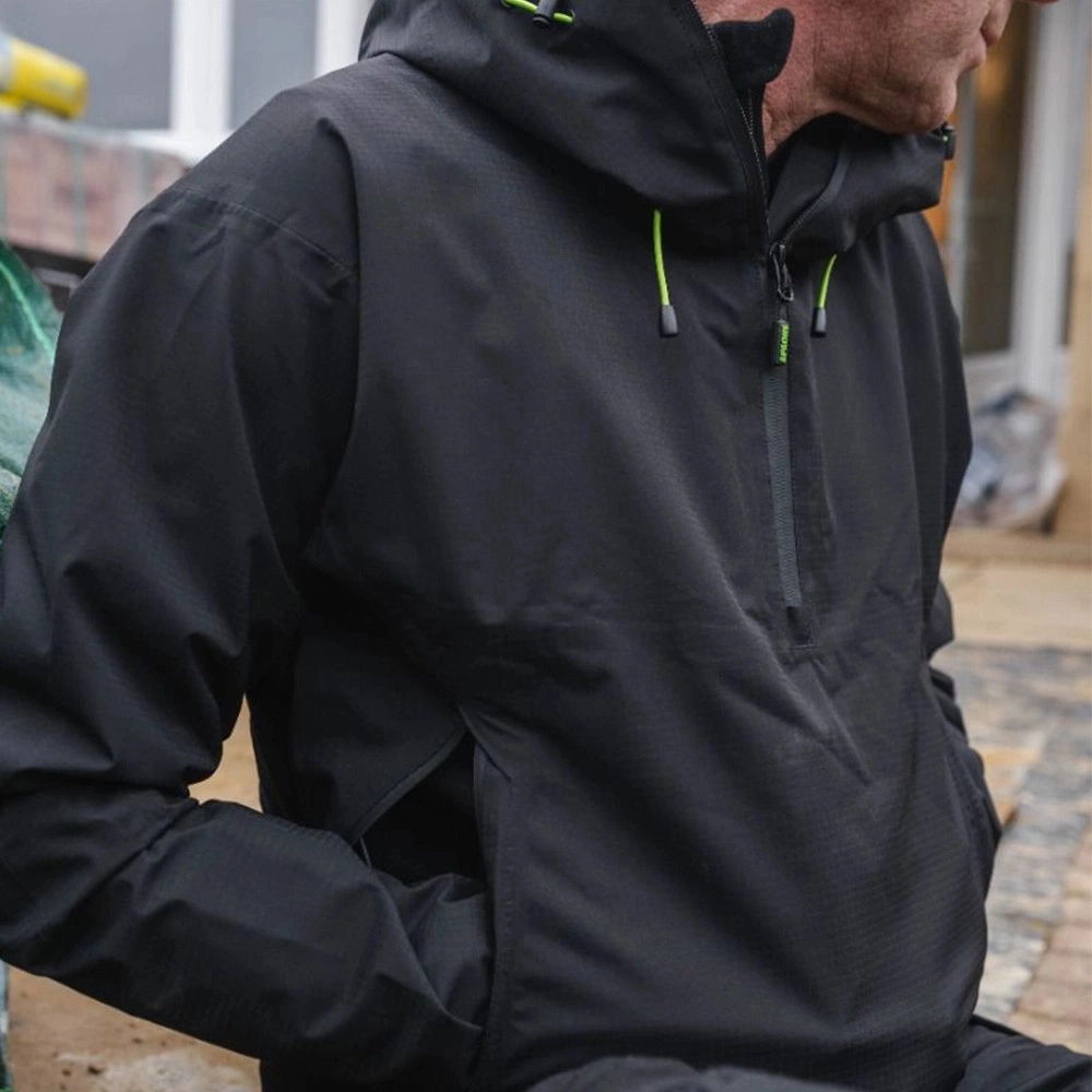 Person wearing a black jacket with a hood, sitting outdoors.