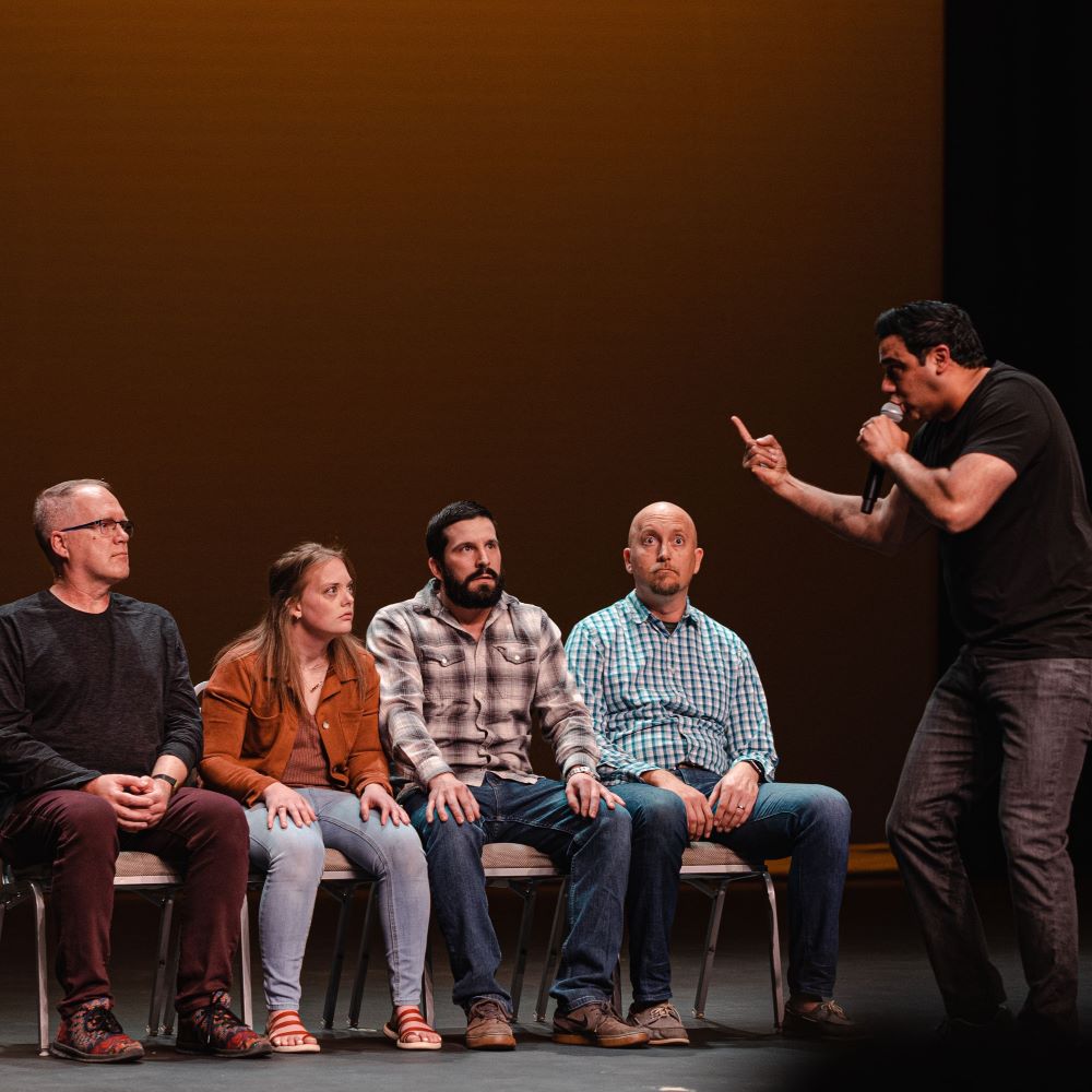 A performer engaging with seated audience members on stage during a show.