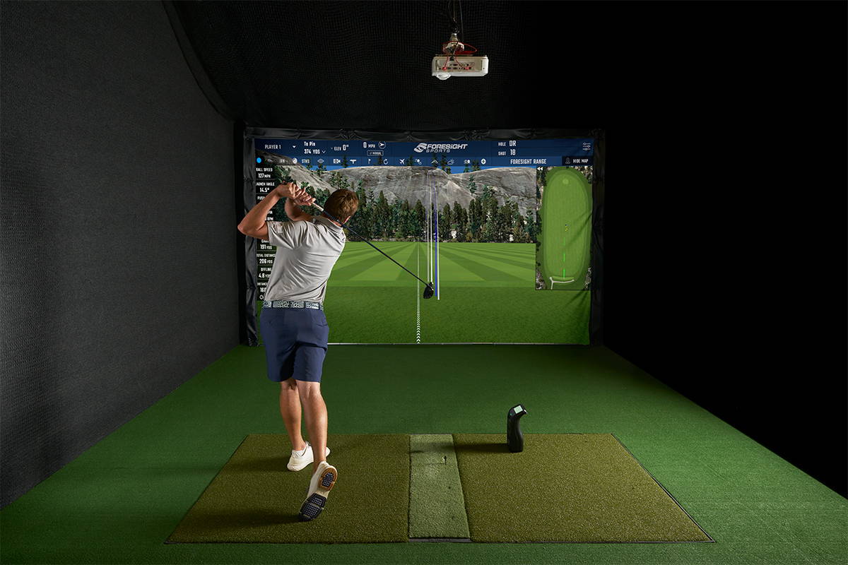 Golfer swinging in a Bushnell Launch Pro golf simulator