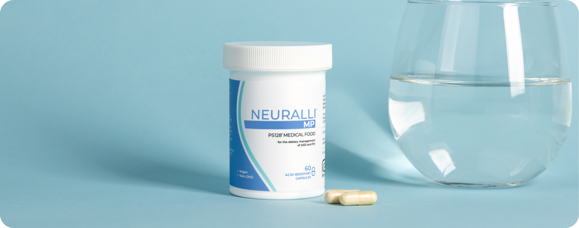Bottle of supplements next to a glass of water on a blue background.
