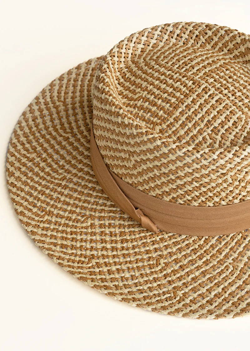 A round brimmed straw hat with a beige ribbon detail