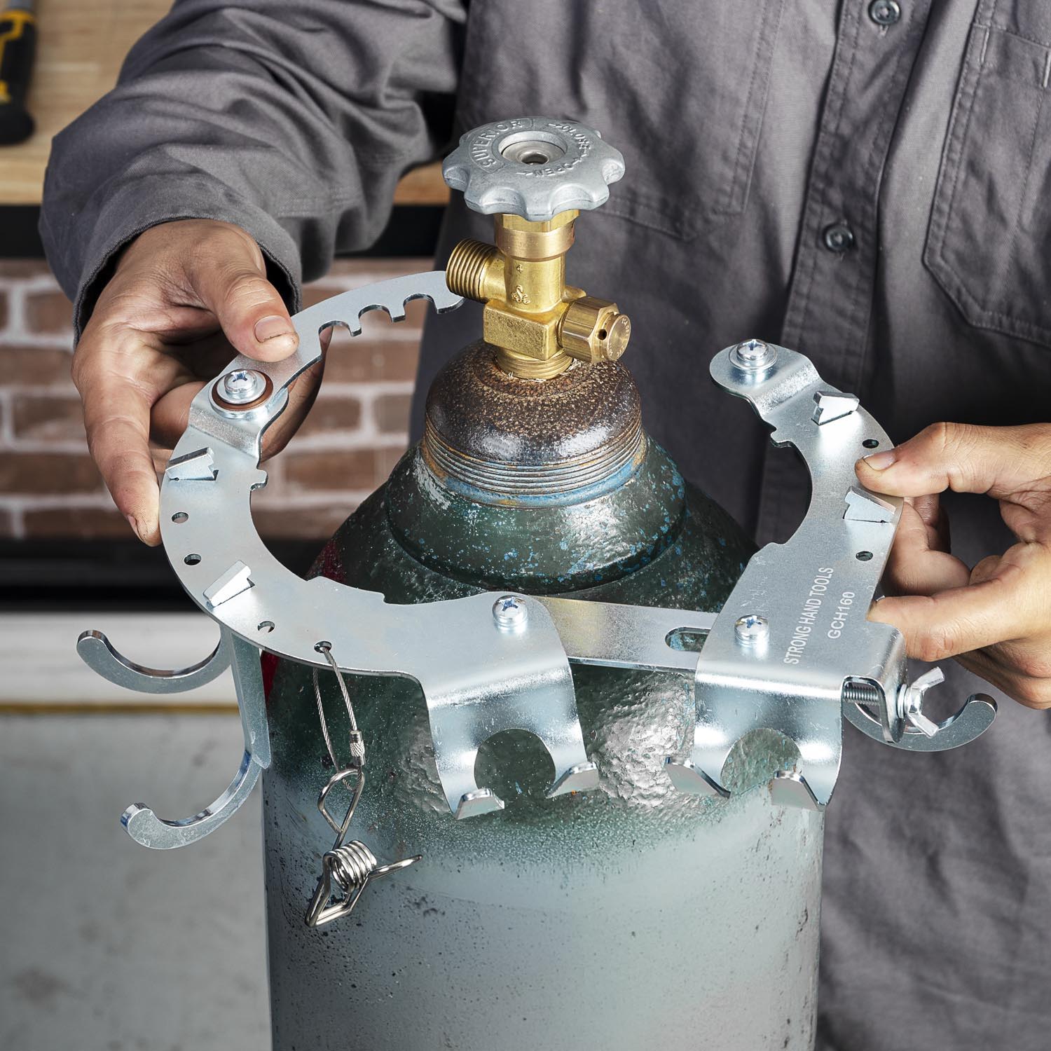 Person holding a metal clamp around a gas cylinder valve.