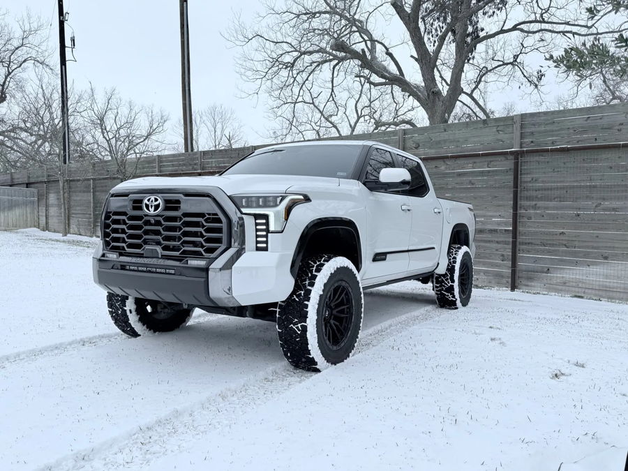 Front three-quarter white Tundra Platinum lifted off-road wheels snow field wooden fence winter Jay's Conductor's Special 228H gallery photo 2