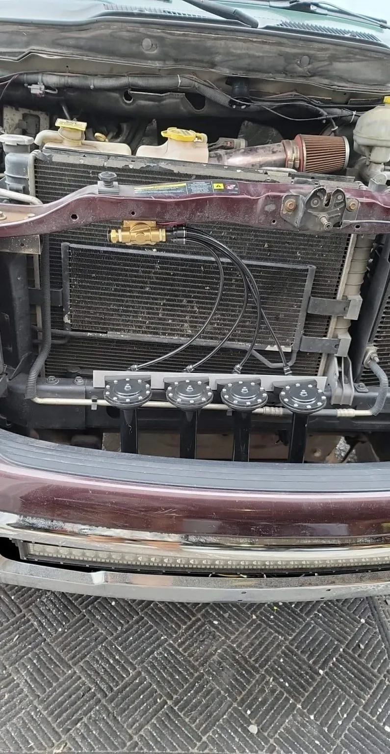 Front-mounted train horn manifold with four black trumpets installed behind the grille of a Dodge Ram 1500