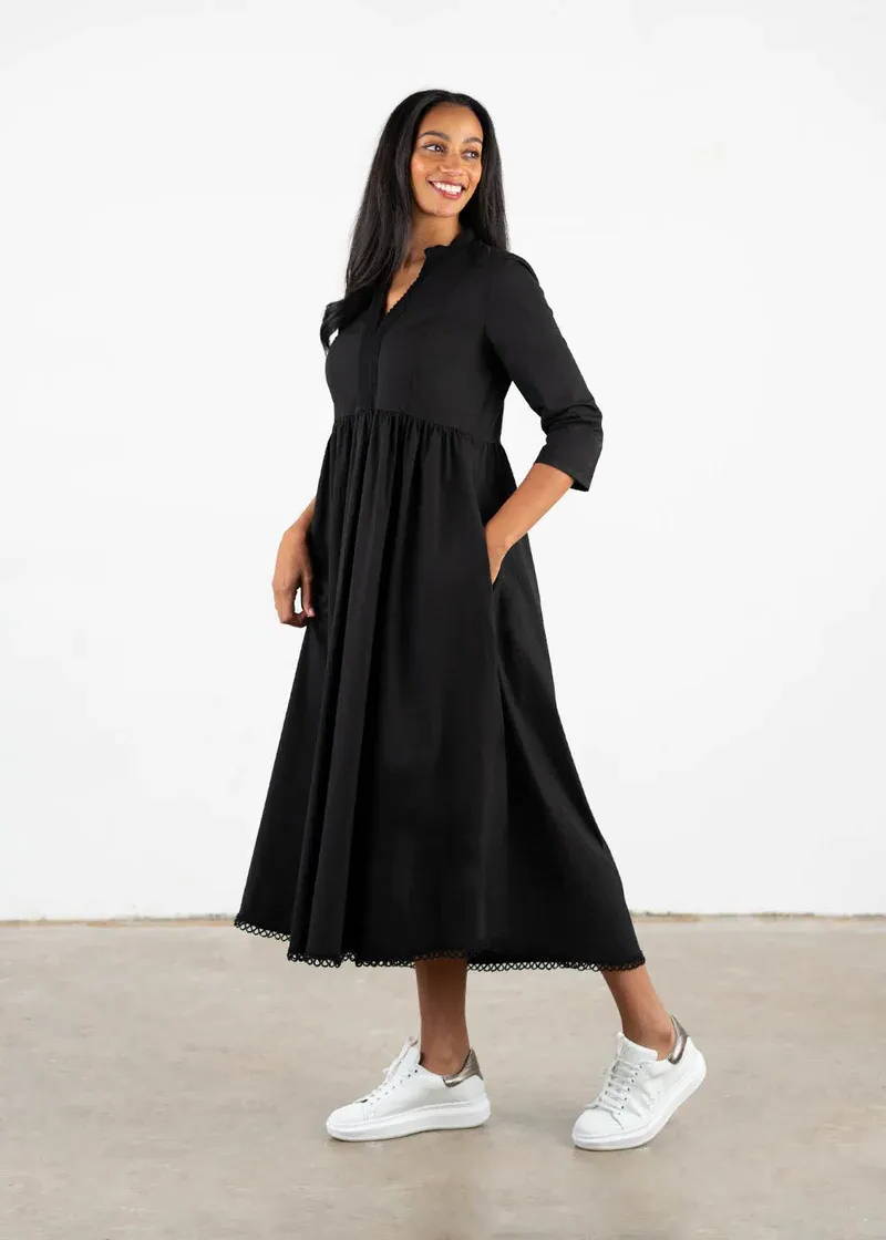 A model wearing a black cotton dres with long sleeves and a midi length