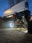 Rear undercarriage of white lifted Ram with LED wheel ring light and aftermarket bumper at dusk