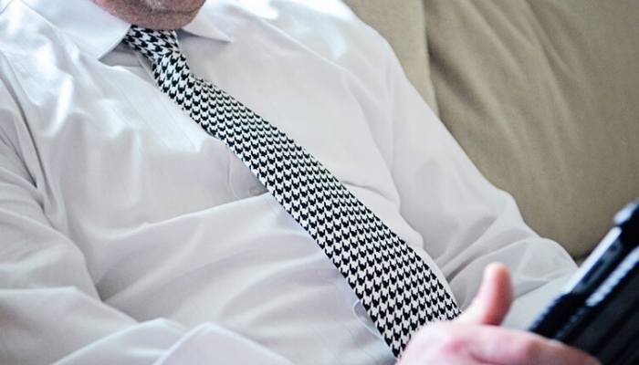 Man wearing houndstooth tie while on tablet