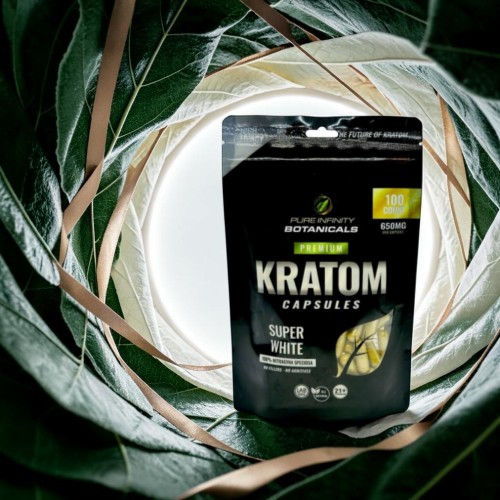 Kratom capsules package surrounded by green leaves.