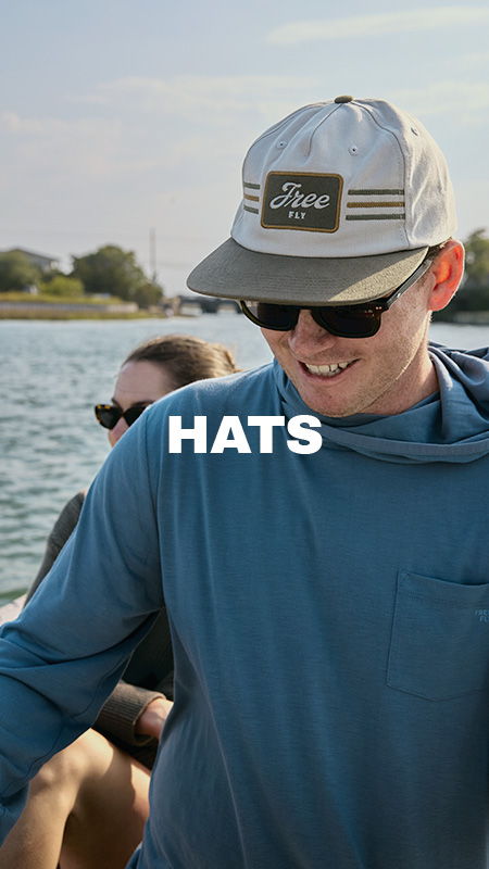 Man wearing a cap, smiling on a boat with a woman behind him.