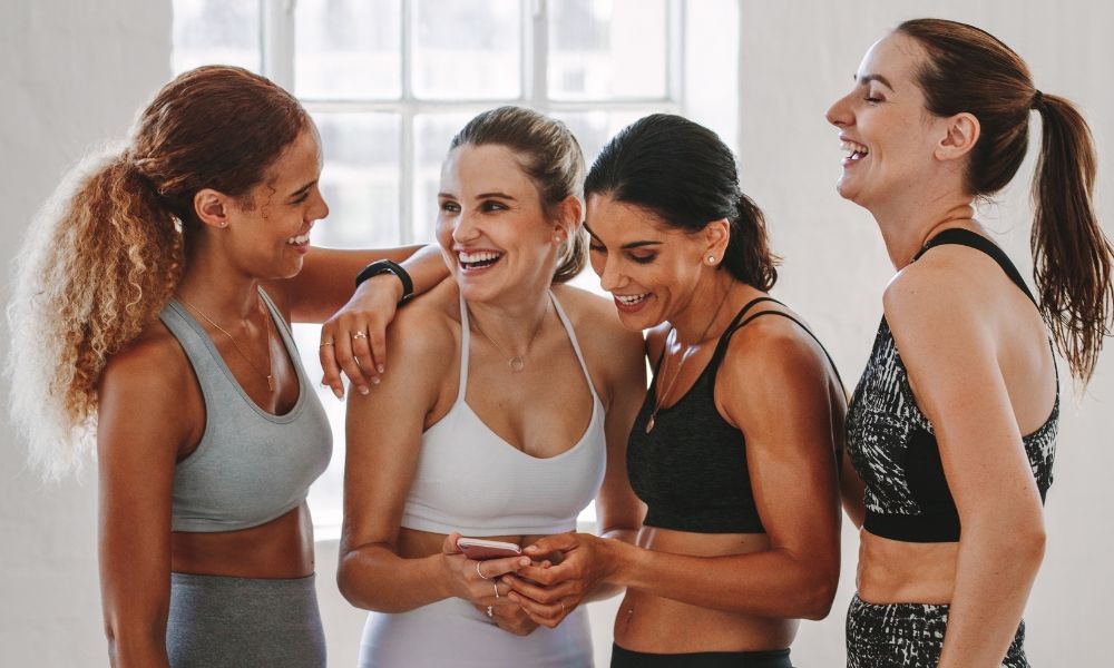 Four women sharing a joyful moment in athletic wear.