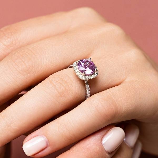 a cushion cut champagne pink sapphire ring with a diamond halo and accented band