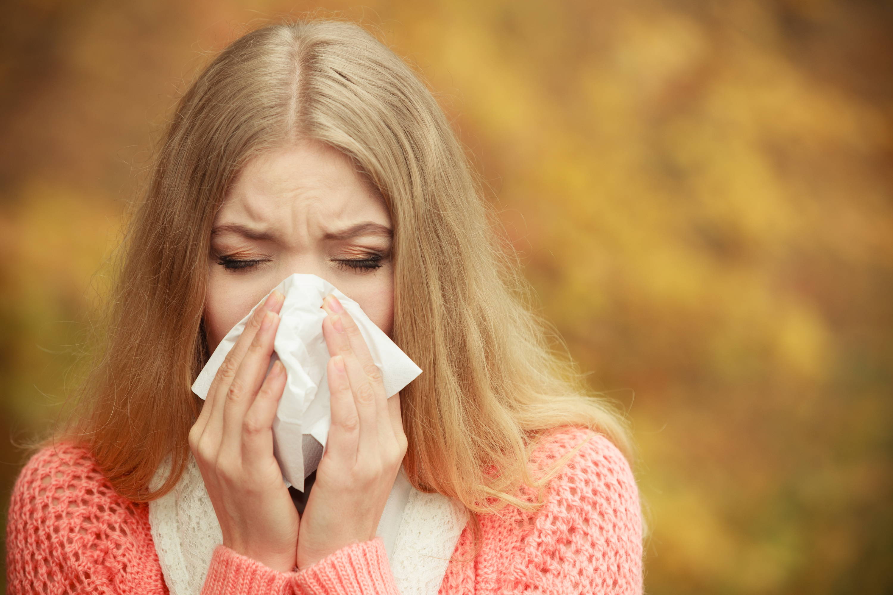 En kvinne nyser. Kløe, nysing og tett eller rennende nese er vanlige symptomer på høysnue. 