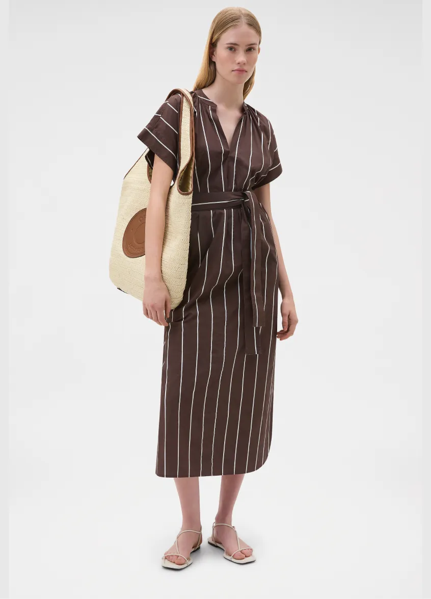 A model wearing a brown striped dress with a tote bag.