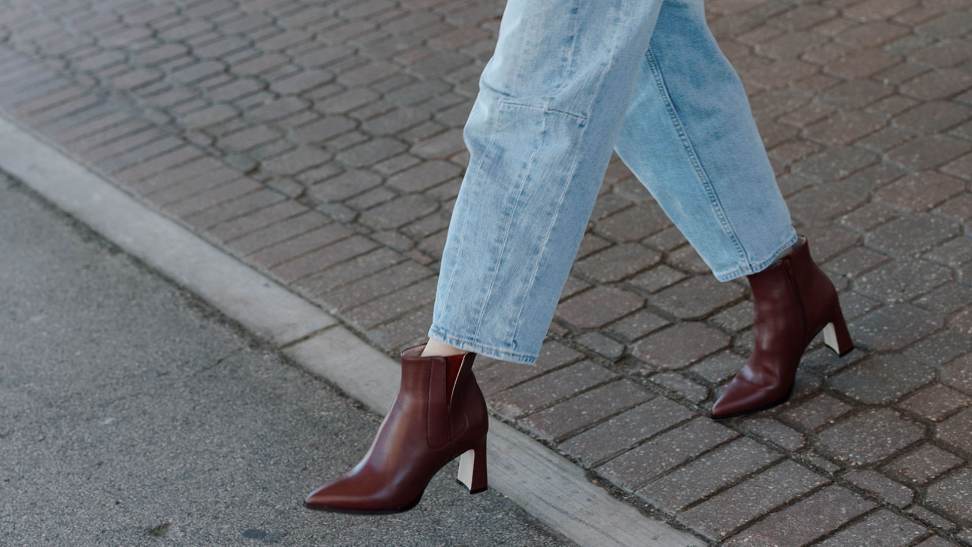 A person walking in brown high-heeled boots and light blue jeans.