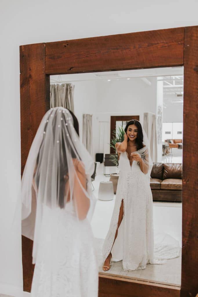 Bride wearing the Aura veil looking into large wood trim mirror