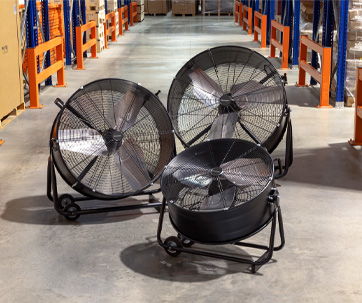 Three industrial fans on a concrete floor in a warehouse setting.