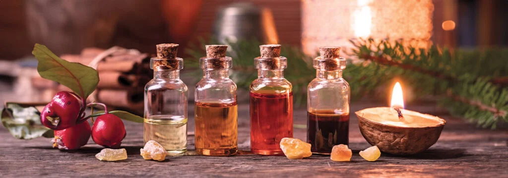 Bottles of essential oils and a candle on a rustic table.