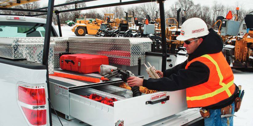 contruction worker using weather guard drawer in bed of truck