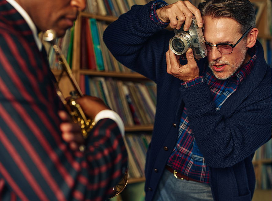 Photographer capturing a musician in a vintage setting with records in background.
