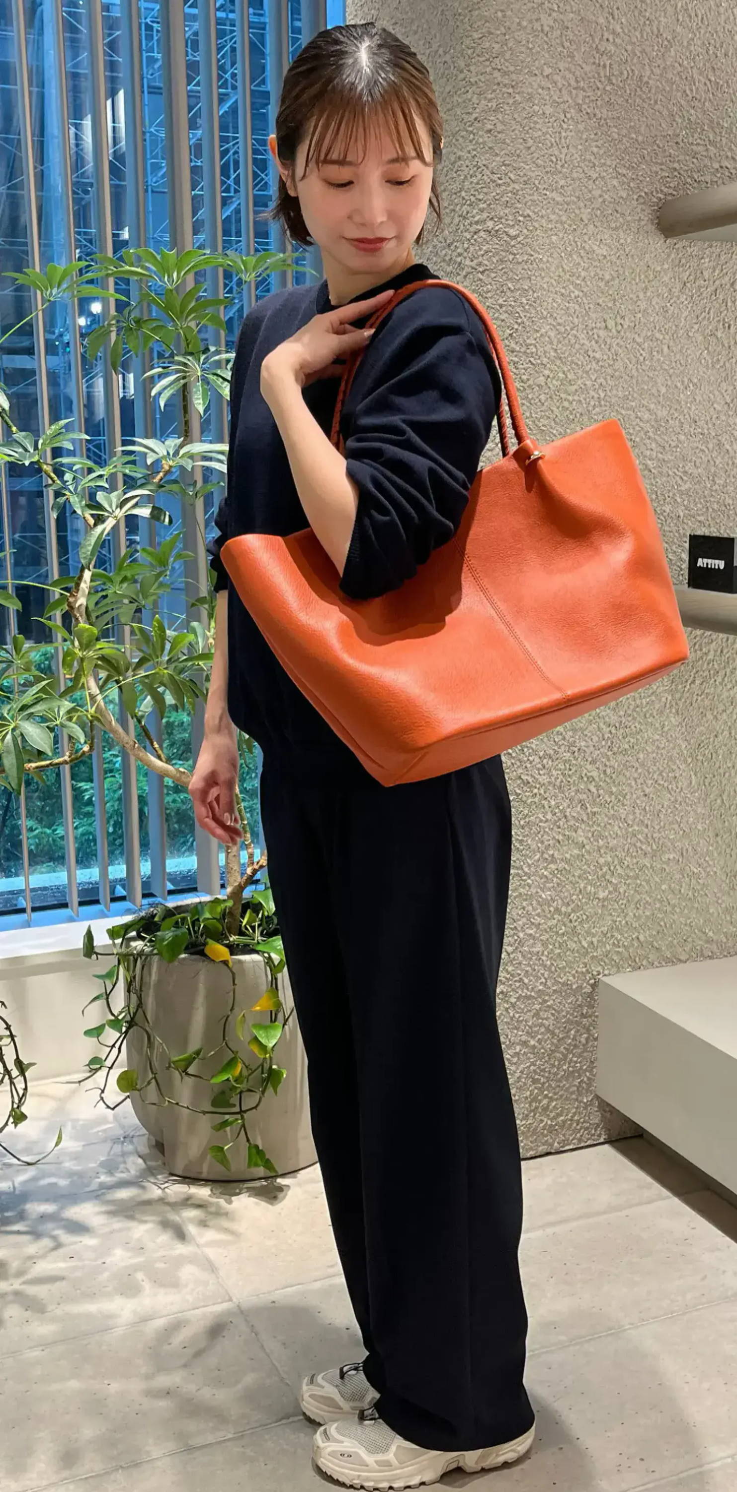 Person holding an orange bag in a modern store setting.