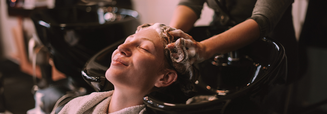 A person receiving a hair wash at a salon.