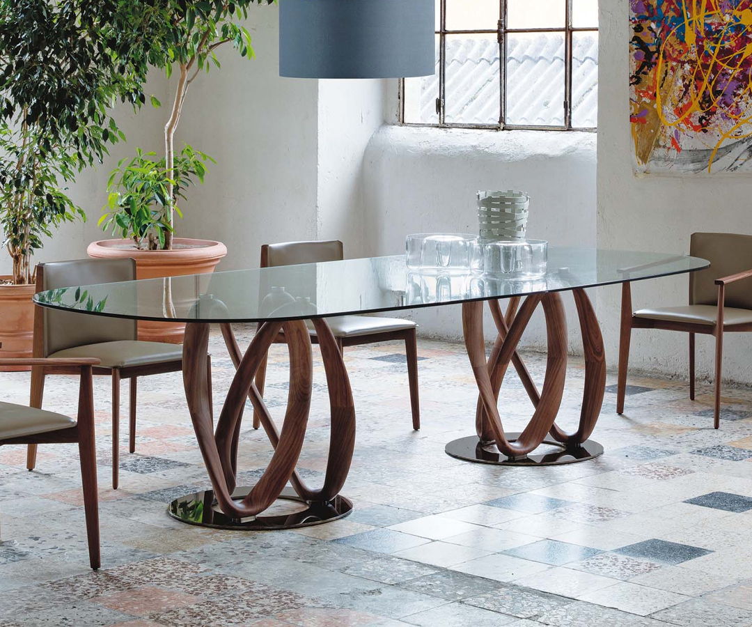 An Infinity dining table by Porada with a glass top and unique wooden base design.